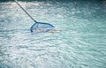 Cleaning swimming pool of fallen leaves with blue skimmer net Royalty Free Stock Photo