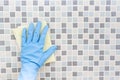 Cleaning tile wall by woman hand with glove, ready to clean house