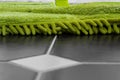 Cleaning tiled floor with a green dry mop head. Royalty Free Stock Photo
