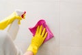 Cleaning tiles in bathroom with pink cloth