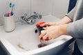 Cleaning vacuum cleaner filter. Woman washing hoover filter with water in bathroom sink at home. Hosehold chores