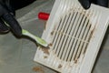 Cleaning a very dirty kitchen exhaust fan from dirt with a brush. A man cleans the parts of a fan with a brush