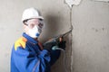 Cleaning the walls of old concrete, for applying new plaster, using a drill, a worker in protective clothing Royalty Free Stock Photo