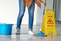 Cleaning, wet floor caution and woman mopping in building for maintenance, health or hygiene. Mop, janitor service and