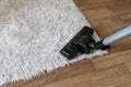 Cleaning white carpet, vacuum cleaner cleaning dust and dirtiness on carpet in living room