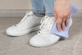 Cleaning white shoes, caring for sneakers. A woman wipes her leather shoes with a wet cloth from dust and dirt. Royalty Free Stock Photo