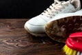 Cleaning of white sneakers on dark wooden background. Brush and solution of water and detergent Royalty Free Stock Photo