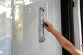 A young man cleans and polishes windows with a sponge