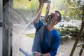 A young man with cleans and polishes windows with a sponge