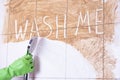 Cleaning woman washes a wall in the bathroom, where it says wash me Royalty Free Stock Photo