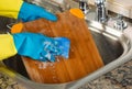 Cleaning Wooden Cutting board inside of Kitchen Sink with sponge Royalty Free Stock Photo