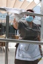 A cleaning worker wearing protective mask clean a glass in a terrace in a hotel in Mallorca vertical