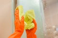 Cleanness in every move. Pretty brunette cleans mirror with help of yellow cloth and special mean of cleaning.