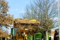 Cleans the sidewalk of the city from fallen leaves with an excavator