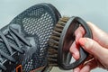 cleans sports shoes, woman cleans shoes with a brush. Sneakers after running. Royalty Free Stock Photo