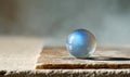 A clear ball with a blue hue sits on a stone surface Royalty Free Stock Photo