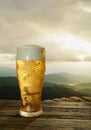 Clear beer glass with full cold beer and foam at the mouth of the glass And water droplets adhere to the edges. Plank or wood