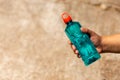 Clear blue green water bottle, the lid is red with a hole in the center for portability, natural background. With the hand held Royalty Free Stock Photo