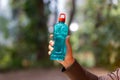 Clear blue green water bottle, the lid is red with a hole in the center for portability, natural background. With the hand held Royalty Free Stock Photo