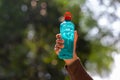 Clear blue green water bottle, the lid is red with a hole in the center for portability, natural background. With the hand held Royalty Free Stock Photo