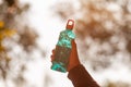 Clear blue green water bottle, the lid is red with a hole in the center for portability, natural background. With the hand held Royalty Free Stock Photo