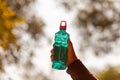 Clear blue green water bottle, the lid is red with a hole in the center for portability, natural background. With the hand held Royalty Free Stock Photo
