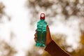 Clear blue green water bottle, the lid is red with a hole in the center for portability, natural background. With the hand held Royalty Free Stock Photo