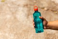 Clear blue green water bottle, the lid is red with a hole in the center for portability, natural background. With the hand held Royalty Free Stock Photo