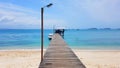 The clear blue sea and Long wooden pier bridge extents from beach to turquoise wave sea