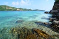 Clear blue sea water with stone and big mountain.