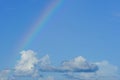 Clear blue sky with cloudscape and rainbow crossing the sky Royalty Free Stock Photo