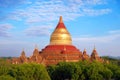 Blue sky above temples surrounded by green vegetation in old Bagan, Myanmar.