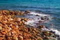 Clear blue water, sea waves running on the red rock shore, sunny summer day by the ocean Royalty Free Stock Photo