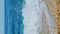 Clear blue waves beat yellow pebbles on beach on sunny summer day, Greece