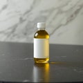 A clear bottle with yellow liquid and a blank white label on a dark surface against a marble backdrop Royalty Free Stock Photo
