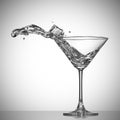 Clear cocktail splash out of glass with ice cube. Royalty Free Stock Photo
