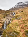 Clear creek stream water flowing over granite stones. Snowy mountains in heavy clouds