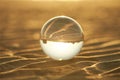 Clear crystal ball are sphere reveals seascape view with spherical placed on the sand beach during sunset. Royalty Free Stock Photo