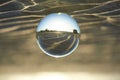 Clear crystal ball are sphere reveals seascape view with spherical placed on the sand beach during sunset. Royalty Free Stock Photo