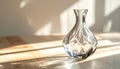 Crystal vase with diamondcut pattern on light wood table in sunlit room Royalty Free Stock Photo
