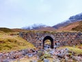 Clear curved stream river below old stony bridge. Mountain sheep path