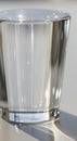 A clear, cylindrical glass filled with water is on a light surface. The glass has a smooth texture Royalty Free Stock Photo