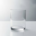 A clear, cylindrical glass stands on a smooth, white surface against a light grey Royalty Free Stock Photo