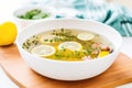 clear detox broth with floating herbs and lemon slices, detoxifying