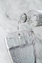 Clear drinking carbonated water is poured into glass on light background. Plastic bottle, splash, beverages, macro, close up, Royalty Free Stock Photo