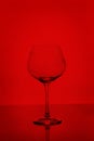 Clear empty wine glass isolated on red