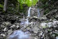 Clear and fresh mountain spring water flows and splashes over a stone down a waterfall - long time water exposurephoto Royalty Free Stock Photo