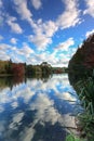 Reflections of fluffy clouds and autumn foliage in a lake