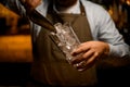 clear glass in bartender hand and pouring pieces of ice into it using steel scoop Royalty Free Stock Photo