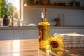 clear glass bottle with golden sunflower or olive oil on table with sunflower and stack of clean towels against backdrop
